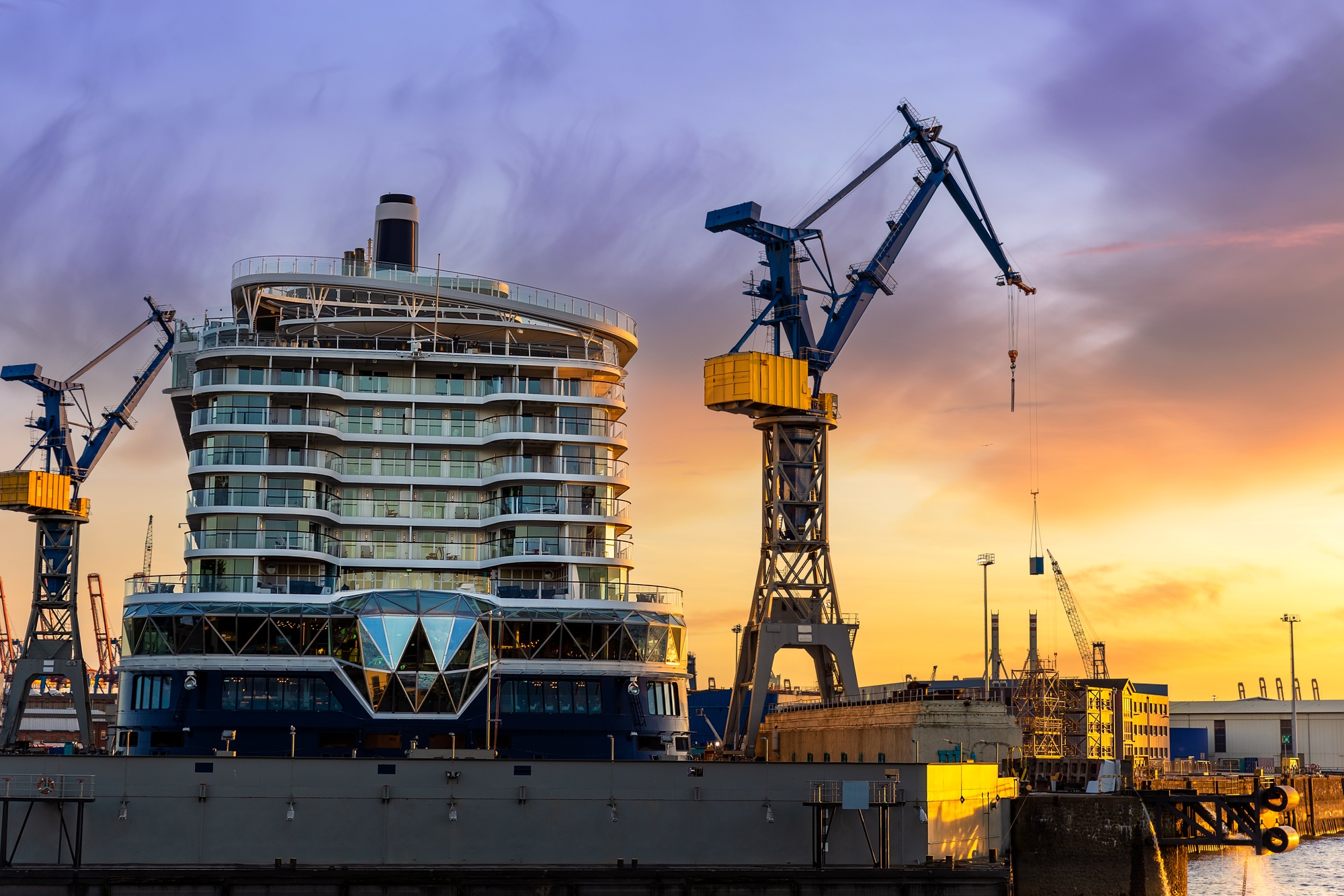 Scenic back view large modern luxury cruise ship liner under construction building cranes at dry